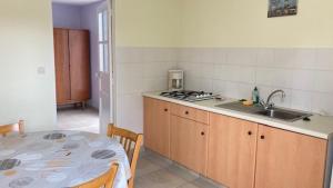 uma cozinha com uma mesa, um lavatório e uma bancada em Au Pibolon des bois em Saint-Hilaire-de-Riez