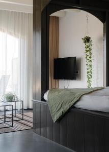 um quarto com uma cama e uma televisão na parede em Bed en Breakfast Hartenlust kamer de Bedstee em Bodegraven