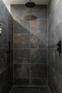 uma casa de banho com um chuveiro com azulejos pretos em Bed en Breakfast Hartenlust kamer de Bedstee em Bodegraven