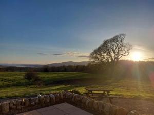 a picnic table in a field with the sun setting at Disdow House; luxury 5 bedroom house with views in Gatehouse of Fleet