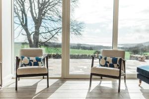 two chairs sitting in front of a window at Disdow House; luxury 5 bedroom house with views in Gatehouse of Fleet