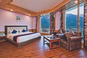 een slaapkamer met een bed, een bank en een stoel bij Goroomgo Hotel BD Resort Manali - Excellent Stay with Family, Parking Facilities in Manāli