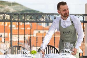 un uomo in piedi davanti a un tavolo con bicchieri da vino di Boutique Hotel Stari Grad a Dubrovnik