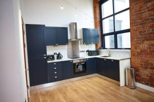 a kitchen with blue cabinets and a brick wall at The Garnet Suite in Manchester