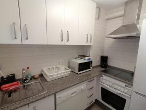 a kitchen with white cabinets and a microwave at PASEO MARITIMO in Barbate