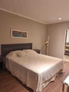 1 dormitorio con 1 cama con colcha blanca en Confortabile Apart en San Fernando del Valle de Catamarca