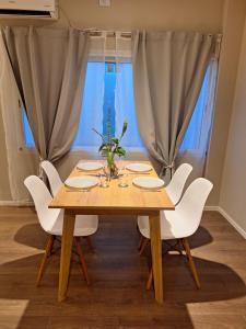 a dining room table with white chairs around it at Confortabile Apart in San Fernando del Valle de Catamarca +12 photos