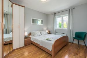 een slaapkamer met een bed en een groene stoel bij Apartment Sara Premium in Funtana