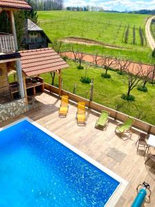 a swimming pool with chairs and a view of a field at Vila GUŠT in Zlatibor
