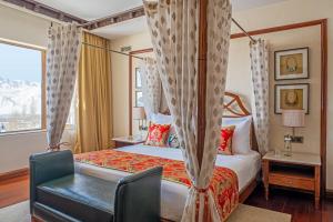a bedroom with a bed and a desk and a window at The Grand Dragon Ladakh in Leh +37 photos