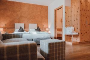 a bedroom with two beds and a couch and a mirror at Residence Hotel Alpinum in Campo Tures