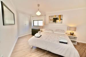 a white bedroom with a large bed and a desk at Palm Tree in São Martinho do Porto