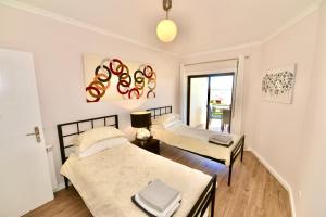 a bedroom with two beds and a window at Palm Tree in São Martinho do Porto