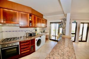 a kitchen with wooden cabinets and a stove top oven at Palm Tree in São Martinho do Porto