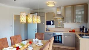 eine Küche mit einem Holztisch mit Stühlen und einer Tableasteryasteryasteryastery in der Unterkunft 54° Nord Wohnung 3 in Grömitz