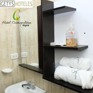 y baño con lavabo, espejo y toallas. en Hotel Cosmopolitan Bogota, en Bogotá