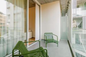 2 sillas verdes en el balcón de un edificio en ONOMO ALLURE ABIDJAN BAOBAB en Abiyán
