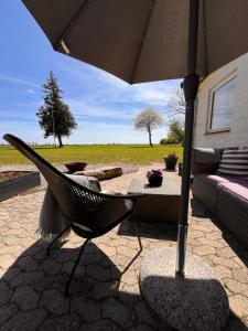 eine Terrasse mit einem Stuhl, einem Sonnenschirm und einer Couch in der Unterkunft Munkgaard Bed & Breakfast in Rødvig