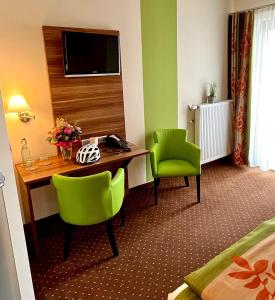 呂德斯海姆的住宿－老德意志葡萄酒吧高級酒店，酒店客房配有书桌和2把绿色椅子