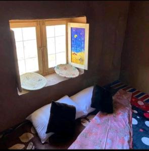 a bedroom with two windows and a bed with pillows at Desert Waves Excursion in Mhamid