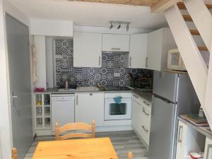 a small kitchen with white cabinets and a wooden table at Natha de la Plage 2000 in Brétignolles-sur-Mer