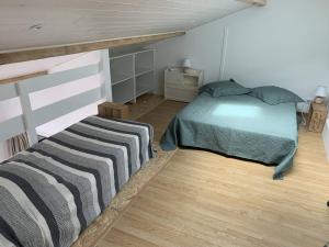 a bedroom with a bed and a wooden floor at Natha de la Plage 2000 in Brétignolles-sur-Mer