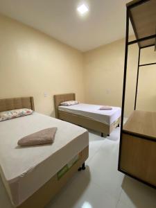 a room with two beds and a mirror at Condomínio Farol das Dunas in Santo Amaro