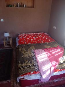 a bedroom with two beds with blankets and a lamp at Desert Waves Excursion in Mhamid