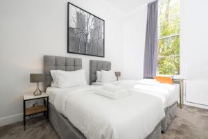 2 weiße Betten in einem Zimmer mit Fenster in der Unterkunft 3 Sloane Gardens in London