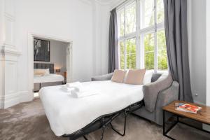een kamer met een bed, een bank en een raam bij 3 Sloane Gardens in Londen