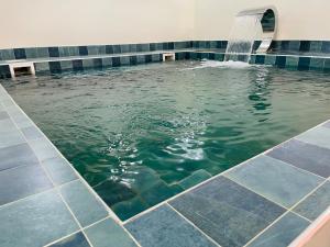 - une piscine d'eau avec une cascade dans un bâtiment dans l'établissement Medina Baye Résidence Boutique Hôtel, à Kaolack