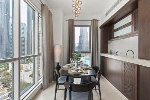 a dining room with a table and chairs and large windows at Stunning 1-Bedroom Apartment with full Burj Khalifa View - 5-min walk to Dubai Mall in Dubai
