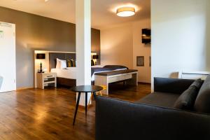 een slaapkamer met een bed, een bank en een tafel bij Bodensee-Hotel Sonnenhof in Kressbronn am Bodensee