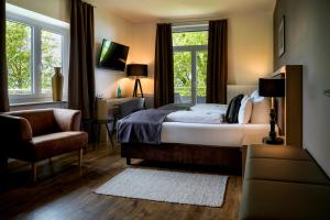 a bedroom with a bed and a chair and a window at Bodensee-Hotel Sonnenhof in Kressbronn am Bodensee +99 photos