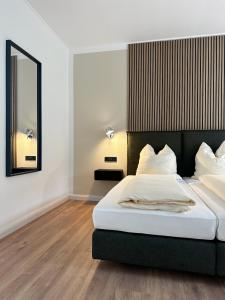 ein Schlafzimmer mit einem großen Bett und einem Spiegel in der Unterkunft Weingut Pieper - Vinothek & Hotel am Drachenfels in Bad Honnef am Rhein