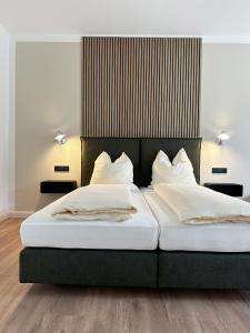 2 Betten mit weißer Bettwäsche und Kissen im Schlafzimmer in der Unterkunft Weingut Pieper - Vinothek & Hotel am Drachenfels in Bad Honnef am Rhein