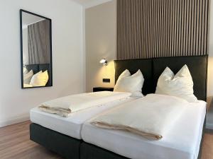 two beds in a hotel room with a mirror at Weingut Pieper - Vinothek & Hotel am Drachenfels in Bad Honnef am Rhein +5 photos
