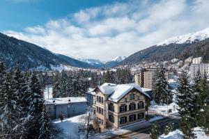 a building in the snow with mountains in the background at Heart of Davos apartments in Davos