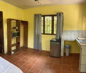 een keuken met gele muren en een tegelvloer bij Orange Cabina in Puerto Jiménez