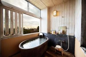 un bagno con vasca e ampia finestra di 伊豆高原の隠れ宿Syuhari守破離 a Ito