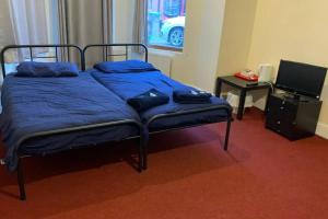 1 dormitorio con 1 cama con sábanas azules y TV en Extra large very big Stander bedroom near station in london, en Londres