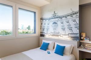 um quarto com uma cama com almofadas azuis e brancas em B&B Hotel Milano Cenisio Garibaldi em Milão