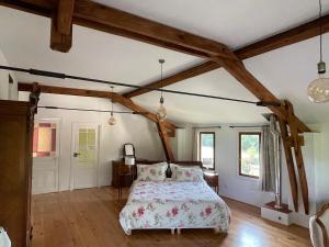 una camera con letto in una stanza con travi in legno di ChezLeMoulin-Boulangerie a Samouillan