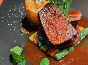 a piece of steak on a plate with vegetables at 古民家やまおか in Iwasaki +31 photos