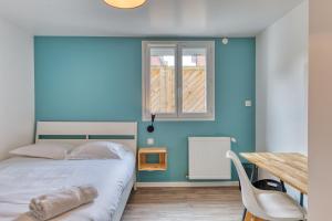 - une chambre dotée d'un mur bleu avec un lit et une table dans l'établissement Céline - Belle Maison moderne, à Le Petit-Quevilly