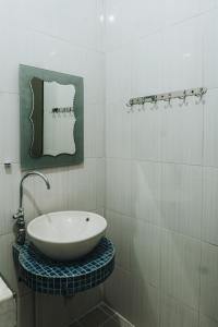 a white bathroom with a sink and a mirror at Sumanas Homestay Ijen in Banyuwangi