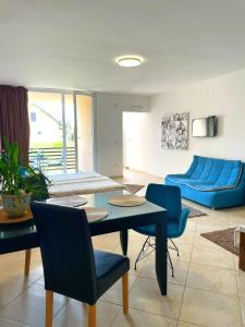 een woonkamer met een blauwe bank en een tafel en stoelen bij SOBE AVA in Palić