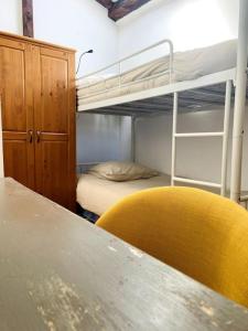 a room with a table and a yellow chair and bunk beds at Le Chaîne - Vieux port centre in La Rochelle