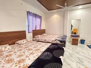 a bedroom with two beds and a ceiling fan at Hotel shree Sidhi vinayak in Ujjain