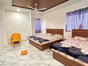 een slaapkamer met 2 bedden en een stoel. bij Hotel shree Sidhi vinayak in Ujjain
